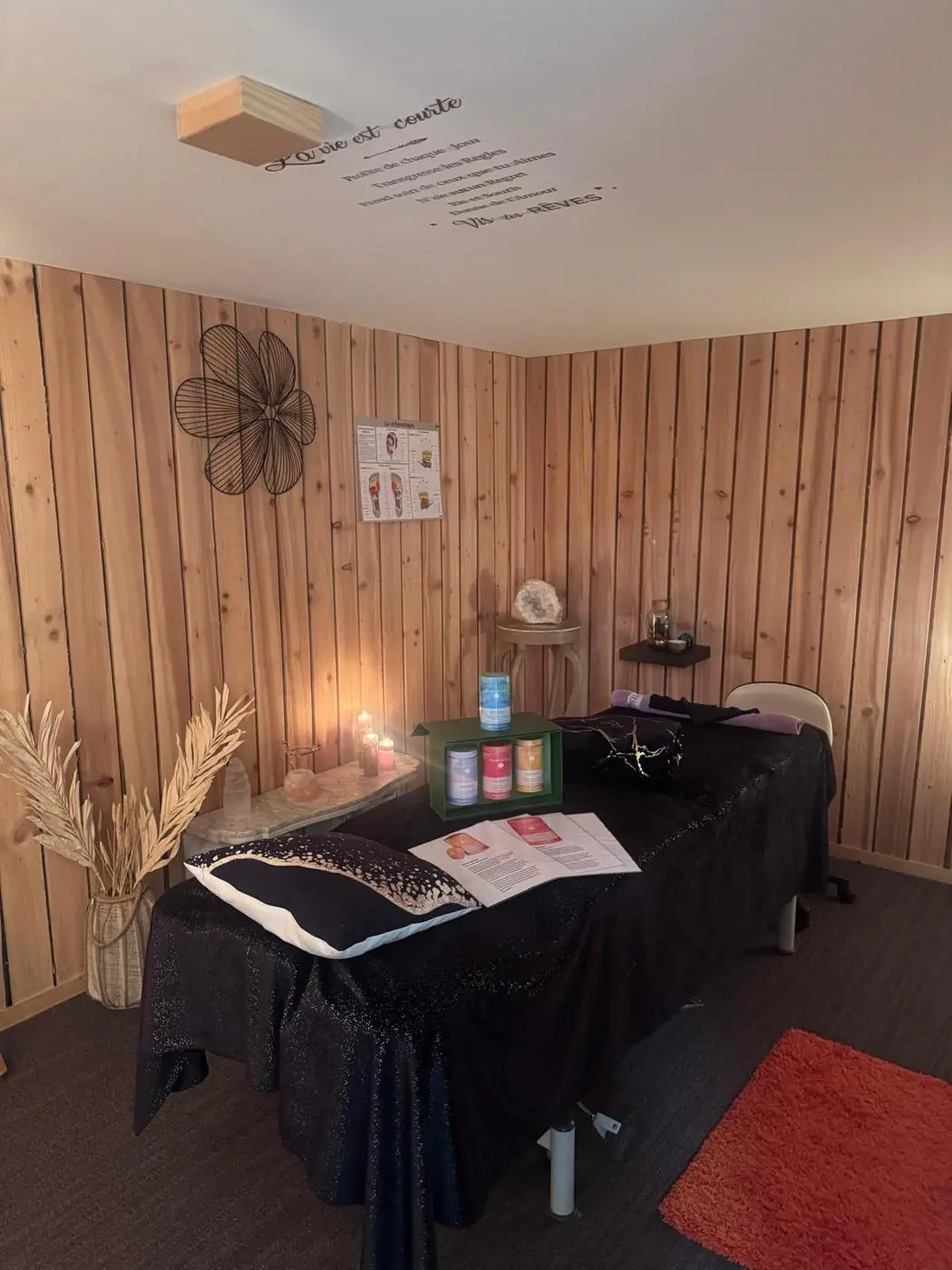 La cabine de La douc'eur : table de soin, mur en lattes de bois, papillon décoratif et citation au plafond